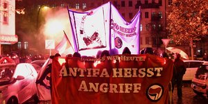 Eine Demo zieht durch Friedrichshain mit Transparent und Bengalofeuer