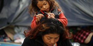 Ein kleines Mädchen sitzt auf den Schultern ihrer Mutter in einer Flüchtlingsunterkunft im mexikanischen Tijuana
