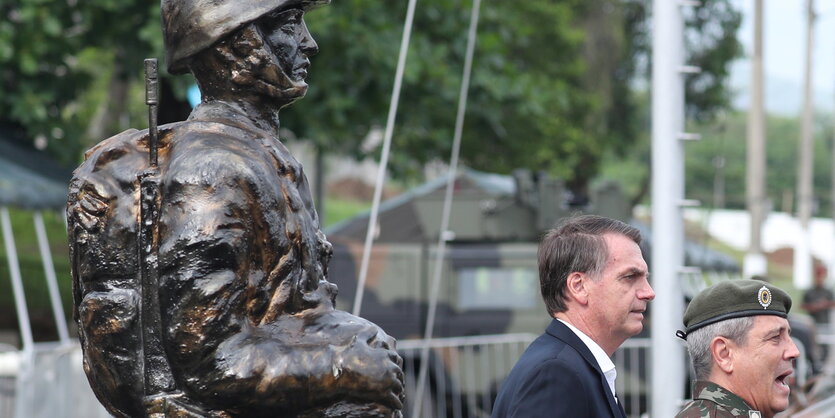 zwei Männer neben einer großen Soldaten-Statue