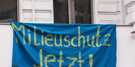 Ein blaues Transparent mit der Aufschrift „Milieuschutz Jetzt!“ hängt unter den Fenstern in einer Gründerzeitfassade