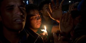 Migranten beten während einer Nachtwache in einer vorübergehenden Unterkunft für mittelamerikanische Migranten in Tijuana