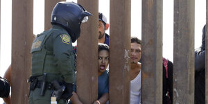 Menschen an einem Grenzzaun zwischen Mexiko und den USA