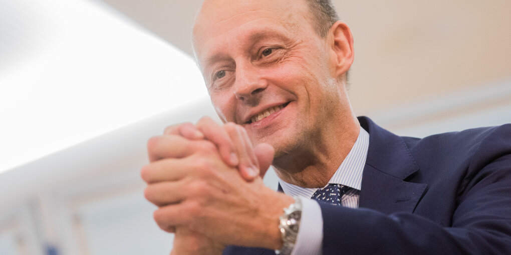 Friedrich merz mit gefalteten Händern und Uhr am Armgelenk.