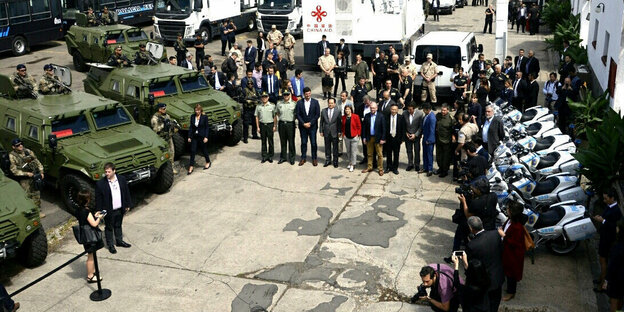 Militärfahrzeuge mit Soldaten vor Menschenmenge