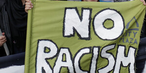 Ein Junge hält ein Transparent mit der Aufschrift "No Racism" hoch