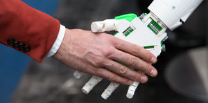 Ein humanoider Roboter gibt einem Menschen die Hand am Stand von ioX Lab bei der IT-Messe CeBIT