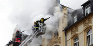 Feuermann auf Leiter vor qualmendem Haus