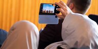 Von hinten sind zwei Frauen mit Kopftuch zu sehen, die mit ihrem Handy eine Podiumsdiskussion auf der Islamkonferenz fotografieren