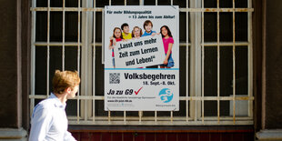 ein Mensch geht an einem Plakat für das Volksbehren „Ja zu G9“ vorbei