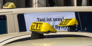 Taxidächer und ein Zettel auf einer Scheibe, auf dem steht "Taxi ist sexy"
