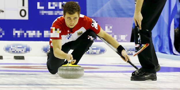 Ein junger Mann, Marc Muskatewitz, spielt konzentriert Curling auf einer Eisfläche