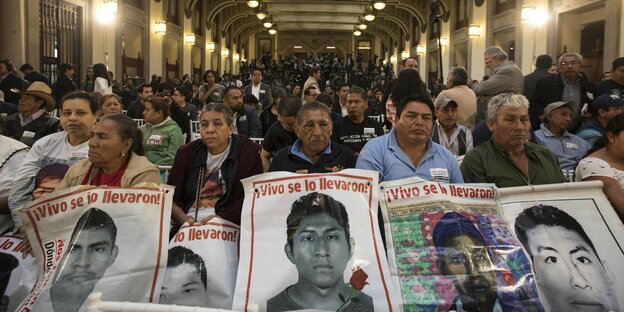 Männer und Frauen halten Plakate mit den Fotos ihrer verschleppten Söhne hoch