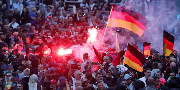 Eine Kundgebung mit Feuerwerkskörpern und Deutschlandfahnen