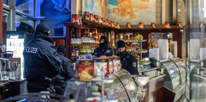 Vermummte Polizisten in einem Eiscafe