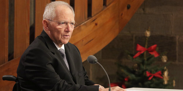 Wolfgang Schäuble sitzt vor Adventskranz in einer Kirche