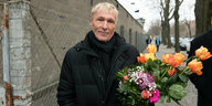 Hubertus Knabe steht mit einem Blumenstrauß vor der Stasi-Gedenkstätte Hohenschönhausen