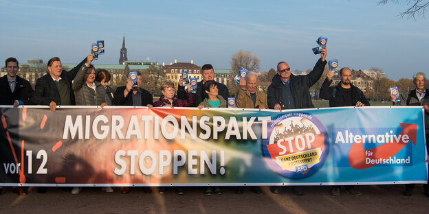 Mitglieder der Meißner AfD stehen während der Landtagssitzung vor dem Landtag und halten einen Banner mit der Aufschrift «Migrationspakt stoppen!»