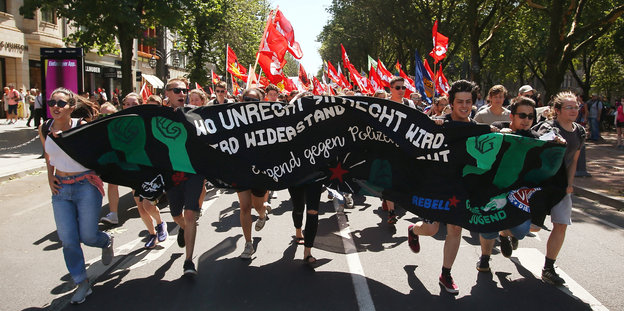 Demonstranten rennen mit einem Banner gegen das geplante neue Polizeigesetz durch die Düsseldorfer Königsallee.