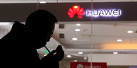 China, Peking: Ein Mann zündet eine Zigarette vor einem Huawei-Store an