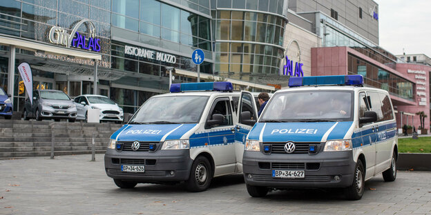 Zwei Polizeifahrzeuge vor einer Shopping-Mall