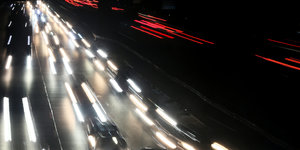 Lichter im Dunkeln. Es sind die Fahrzeuglichter von sich bewegenden Autos im Dunkel.