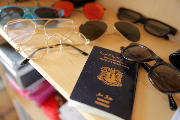 Ein syrischer Pass liegt zwischen verschiedenen Sonnenbrillen