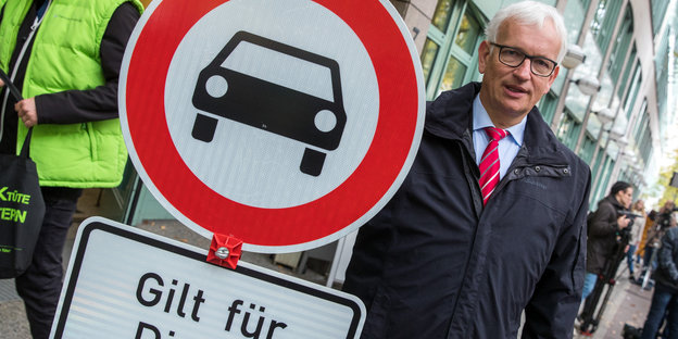 Jürgen Resch, Chef der Deutschen Umwelthilfe, in einem Mantel neben einem Verkehrsschild