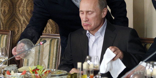 Putin sitzt alleine an einem Konferenztisch, vor ihm steht essen