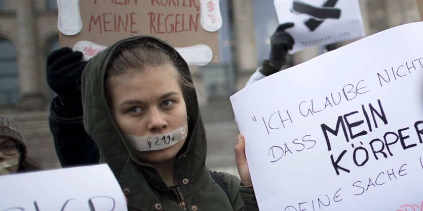 Eine Frau demonstriert, ihren Mund hat sie mit Tape verklebt