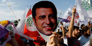 DemonstrantInnen halten Flaggen und ein Bild von Selahattin Demirtas in die Höhe