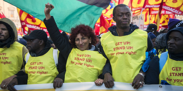Mehrere Menschen mit gelben Westen auf denen "Get up, stand up, for your rights" steht