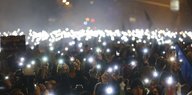 Viele Menschen halten im Dunkeln ihr Smartphone hoch, um Licht zu machen.