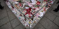 Kerzen und Blumen stehen auf einem Sockel in der Innenstadt von Straßburg
