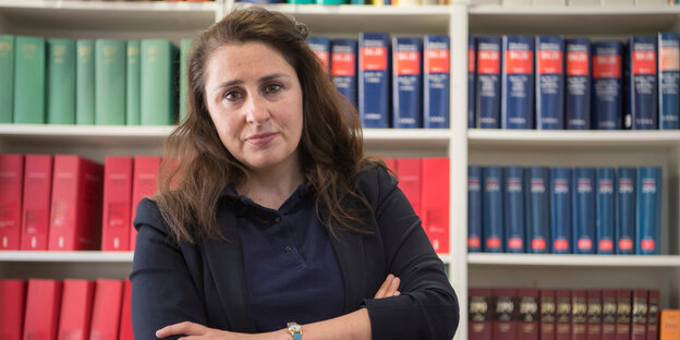 Die Rechtsanwältin Seda Başay-Yıldız steht vor einer Schrankwand mit juristischer Literatur