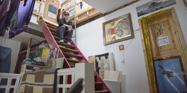 Eine Frau sitzt auf der Treppe des alternativen Wohnprojekts Assenland in Frankfurt am Main
