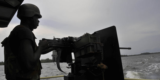 Ein nigerianischer Soldat mit Geschütz auf einem Boot
