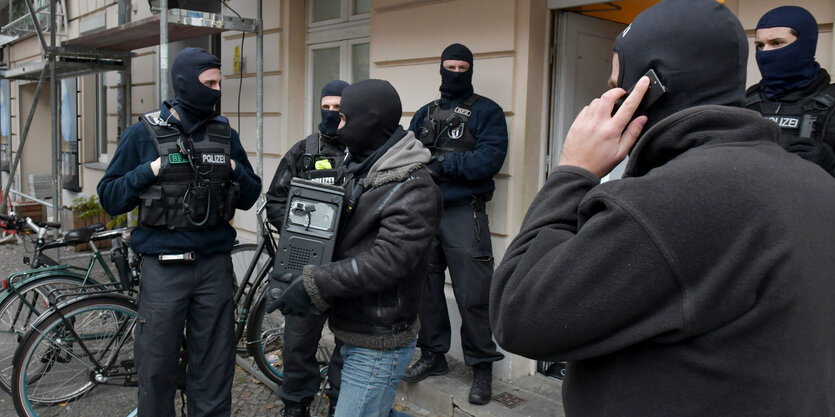 Ein Polizist verlässt mit einem Computer im Arm eine Moschee