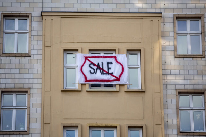 Ein Plakat mit Aufschrift Sale durchgestrichen hängt vor einem Fenster