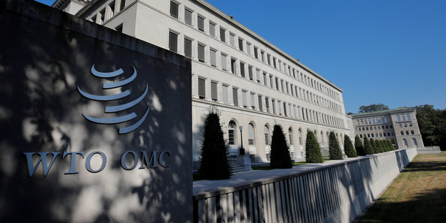 Vor einem großen Gebäude steht ein Schild mit den Buchstaben WTO. Die Abkürzung steht für Welthandelsorganisation