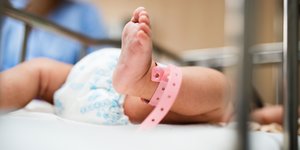 Ein Neugeborenes mit einem Krankenhaus-Bändchen um den Fuß