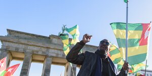 Ein Mann mit der Fahne Togos vor dem Brandenburger Tor