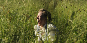 Szene aus dem Film: Eine junge Frau sitzt im Gras und schreit.