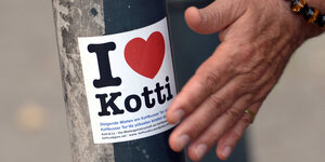 Ein Aufkleber mit der Aufschrift "I love Kotti" wird auf einen Laternenpfahl geklebt.