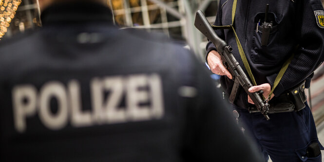 Die Körper von zwei Polizisten. Einer von ihnen hält ein Gewehr