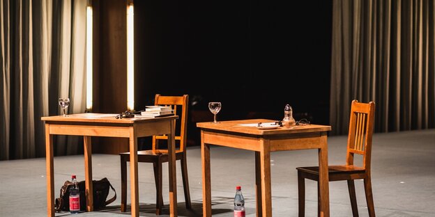 Eine Theaterbühne mit zwei Tischen und Stühlen darauf Eine Theaterbühne mit zwei Tischen und Stühlen darauf