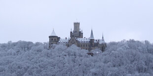 Das Schloss Marienburg in einem weiß verschneiten Wald.