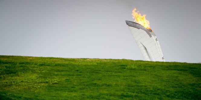 Der Turm mit der olympischen Flamme in Sotschi im Hintergrund, im Vordergrund eine grüne Wiese