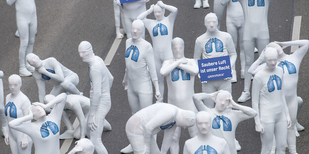 Demonstranten in Ganzkörperanzügen mit aufgemalten Lungen