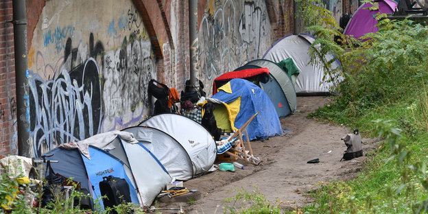Zelte von Obdachlosen stehen an einem Bahnviadukt