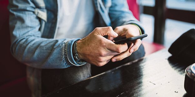 ein Mann tippt etwas in sein Smartphone. Man sieht nur seine Arme und seinen Oberkörper ein Mann tippt etwas in sein Smartphone. Man sieht nur seine Arme und seinen Oberkörper